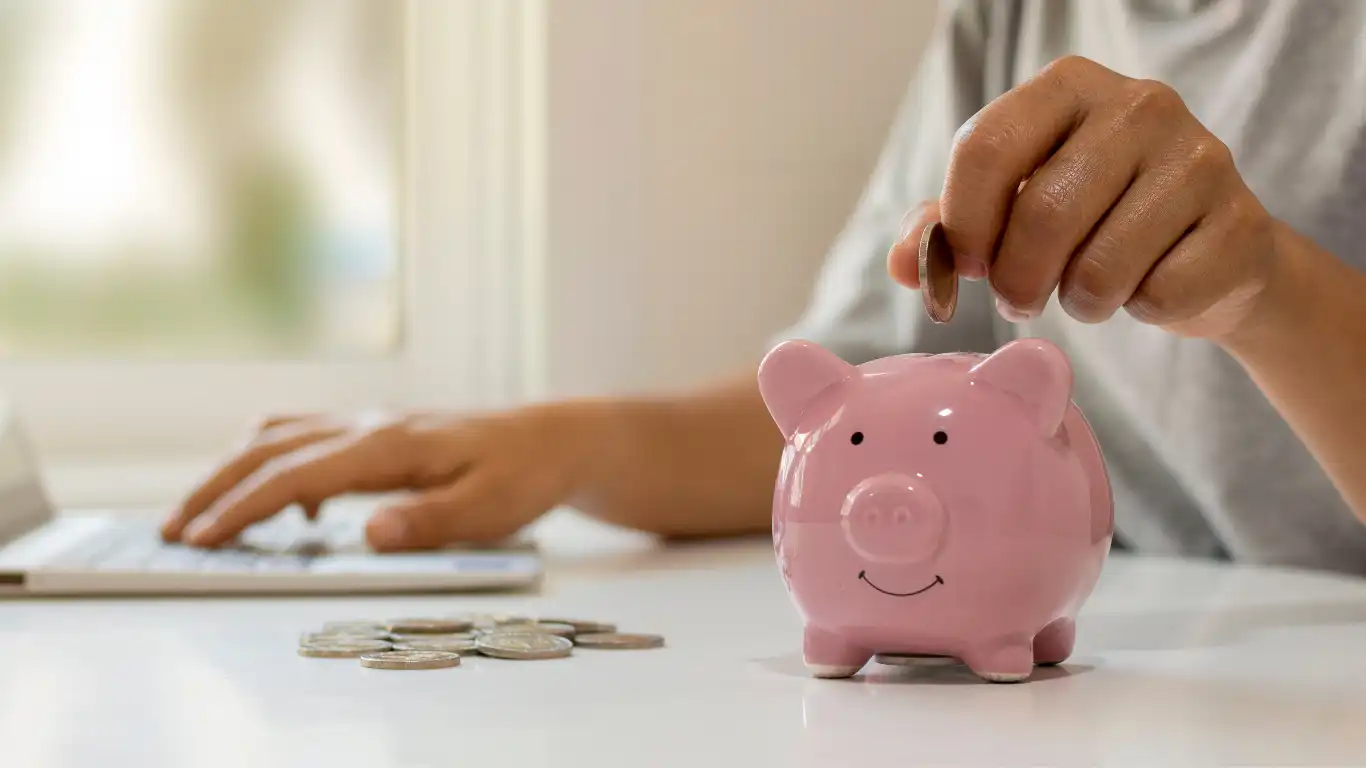 豚の貯金箱に硬貨を入れている