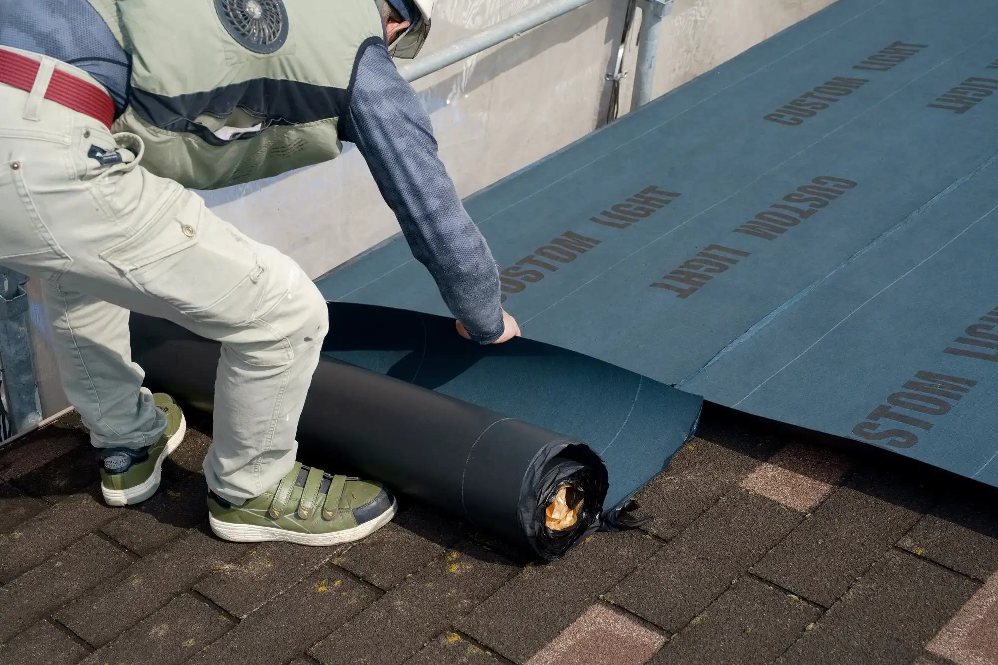 屋根にルーフィング材を貼っている