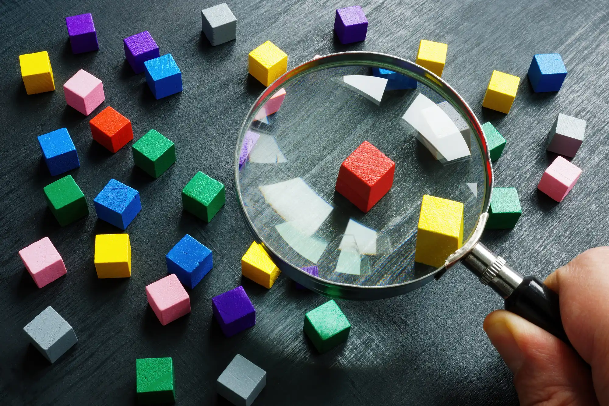 色んな色が塗られた小さい積み木を虫眼鏡で見てる