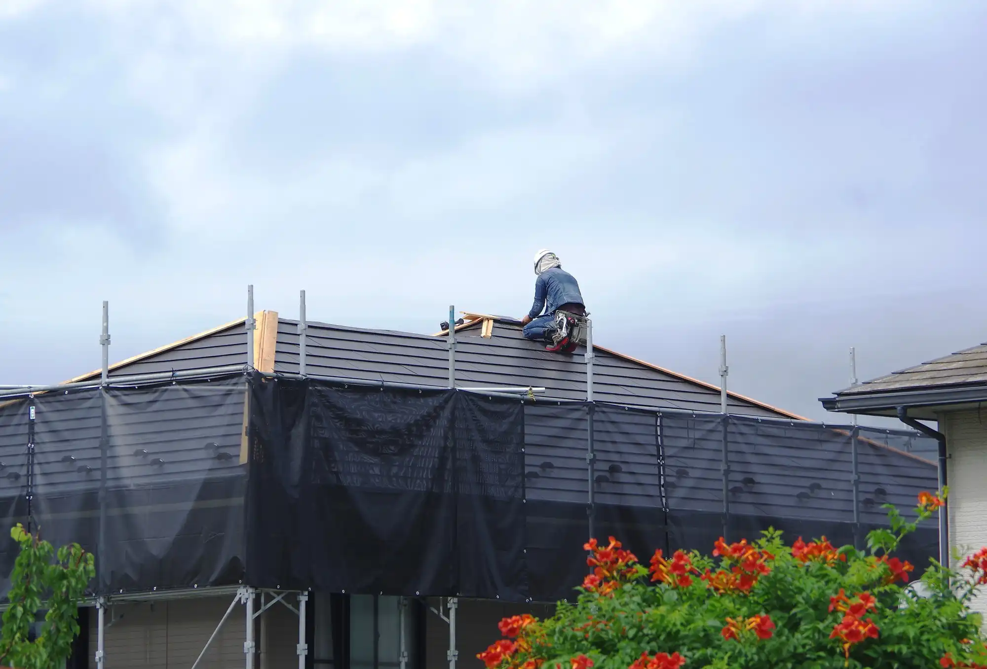屋根に登って修理中の作業員