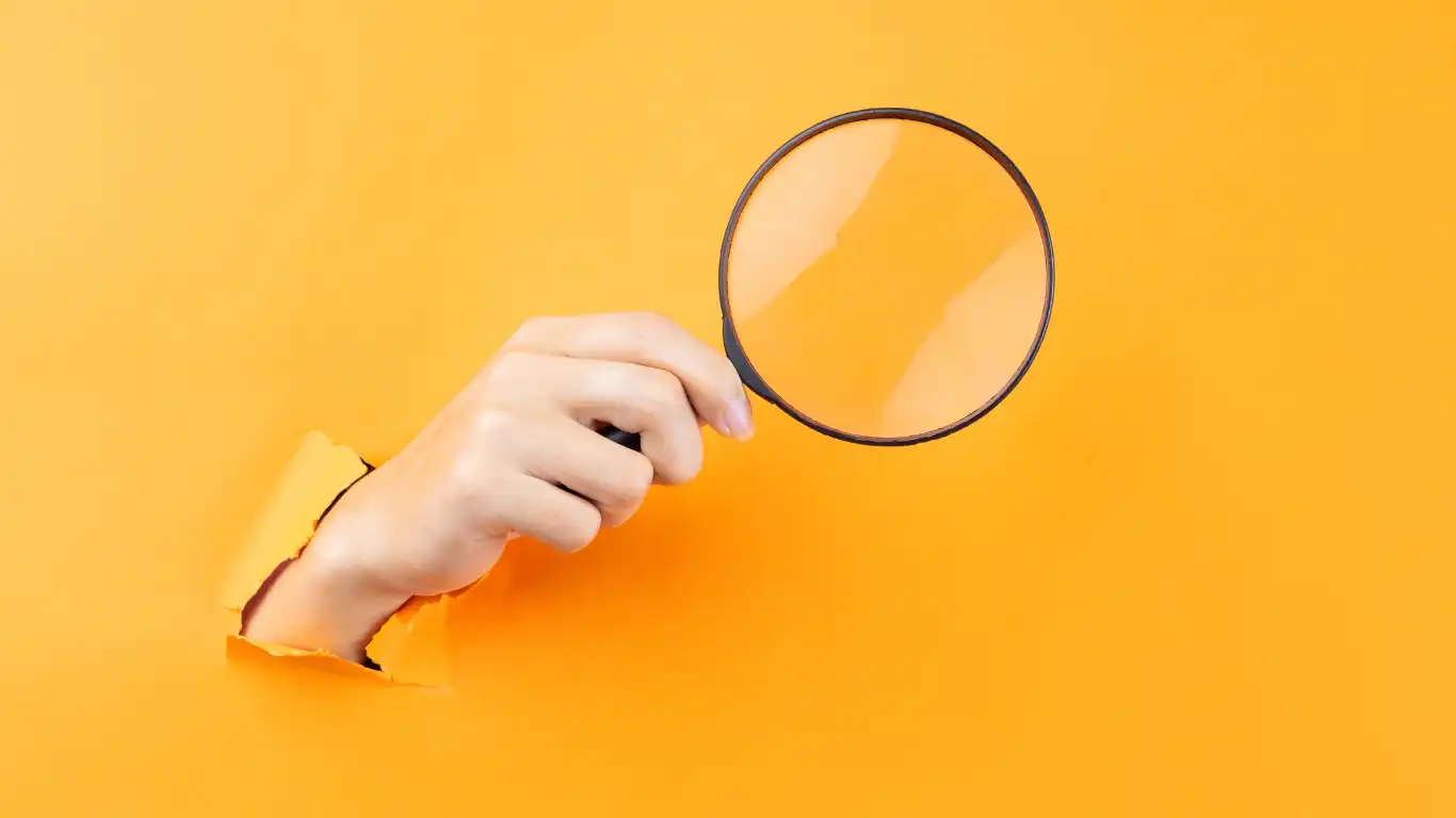 黄色の壁の前で虫眼鏡を持っている