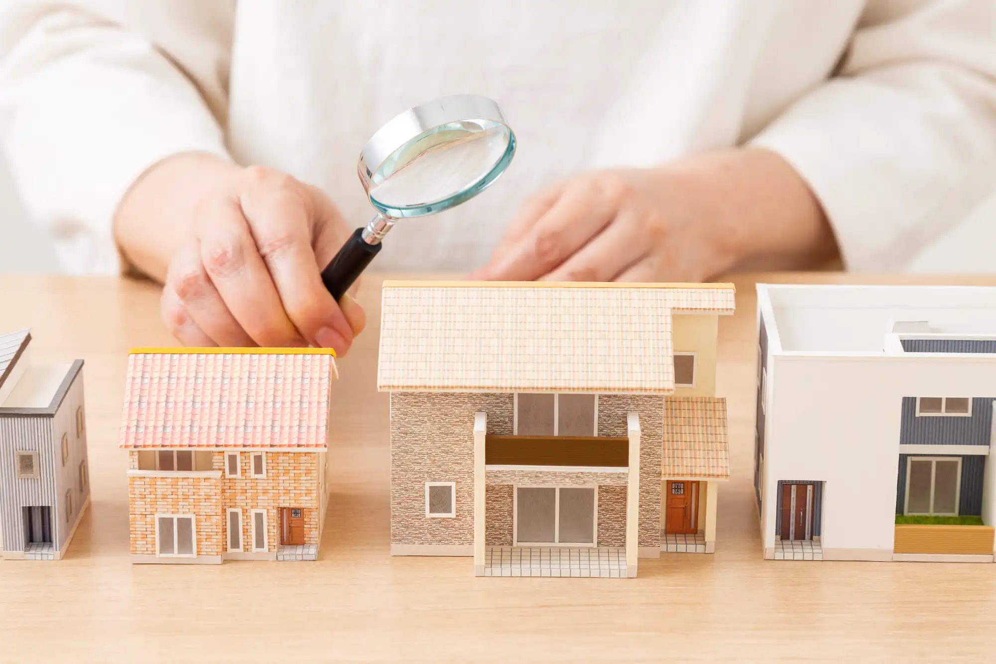 家の模型がいくつか並べらrていて虫眼鏡を持って見ている