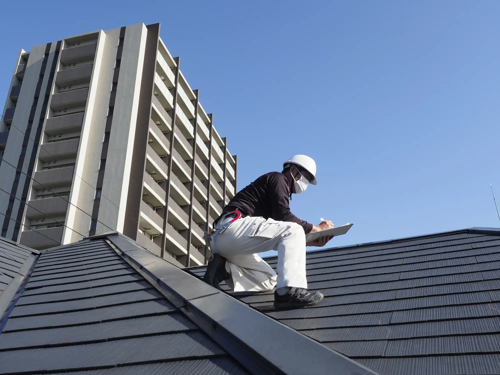 屋根に登り点検する作業員