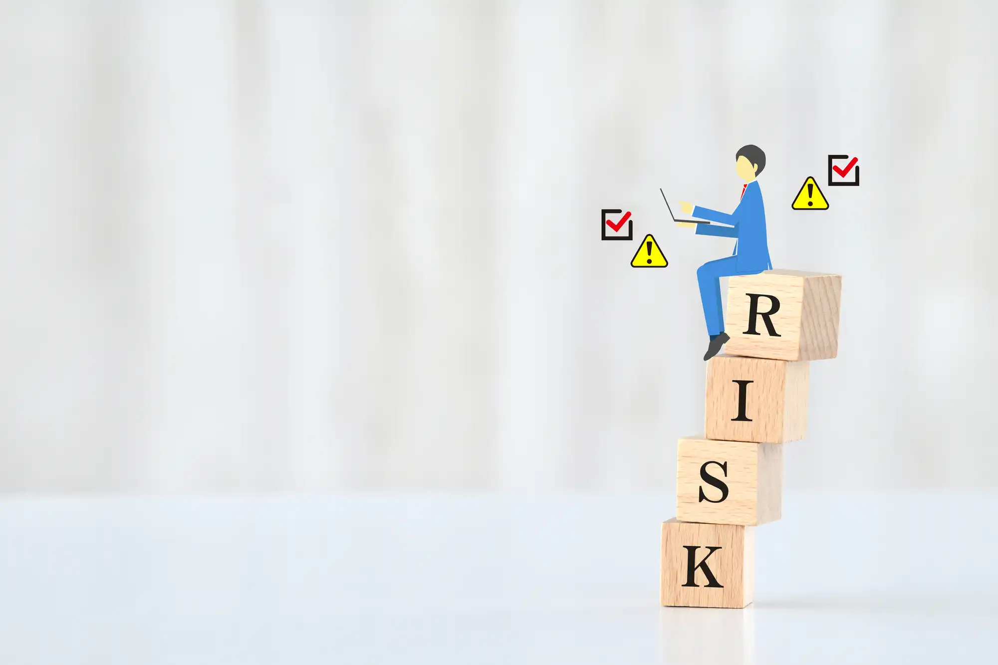 人のイラストがRISKと書かれた積み木に乗っている