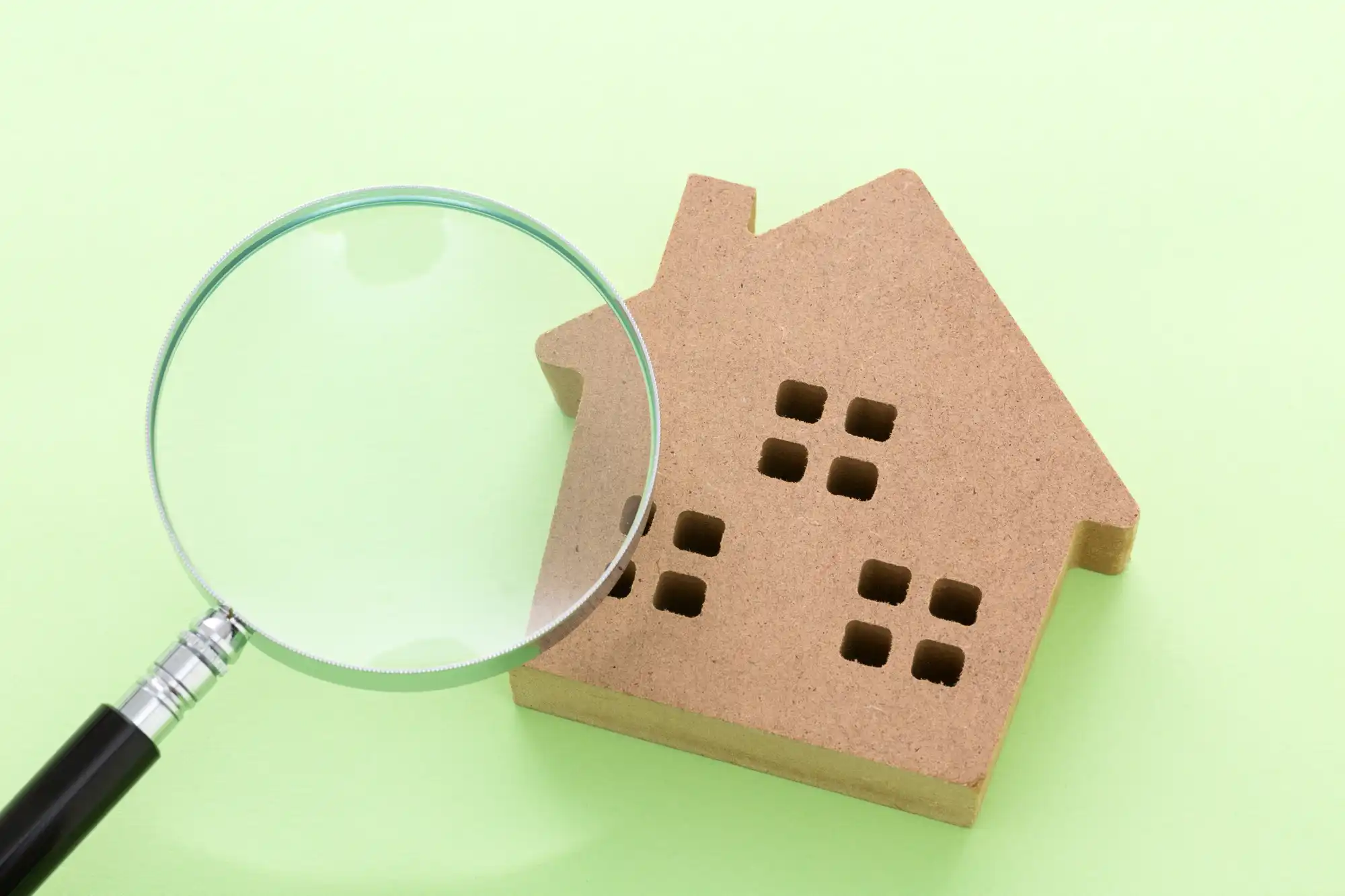 家の模型を虫眼鏡で見ている